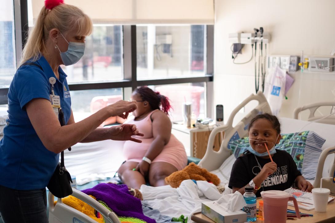 Sally Jo pretends to stir a drink for a child in the hospital